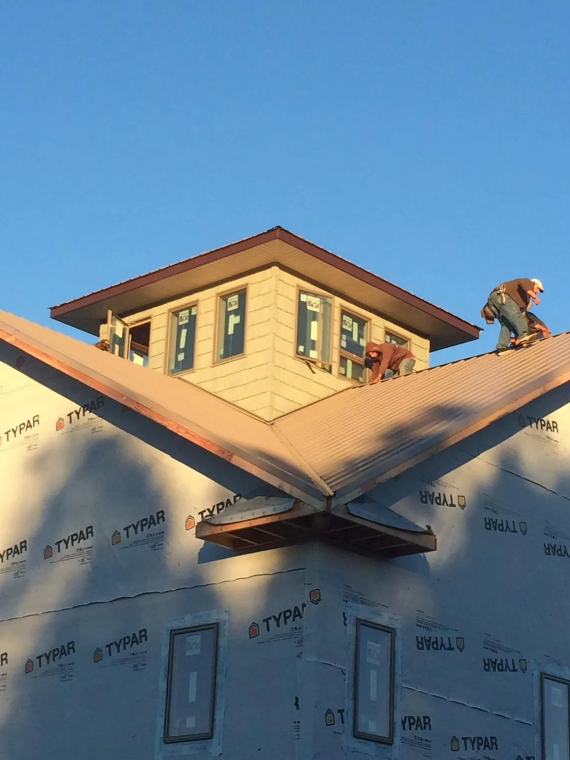 Roofers working around a rooftop cupola on a new metal roof at sunset — Roof Waterproofing in Hermitage by Roofing Brothers